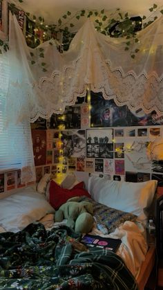 an unmade bed with lots of pictures on the wall and curtains hanging above it