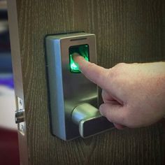 a hand is pressing the button on a door handle with a green light in it