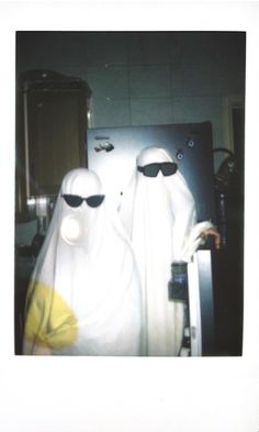 two people dressed in white are standing next to each other with sunglasses on their faces