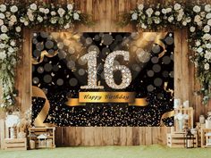 a black and gold 16th birthday party backdrop with flowers, streamers and confetti