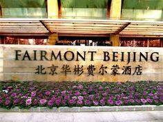 the entrance to the fairmont being building in hong kong, with flowers on the sidewalk