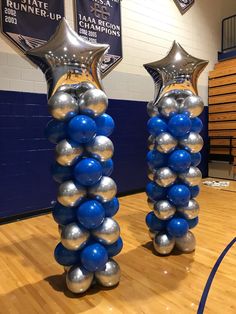 two silver and blue balloons in the middle of a basketball court