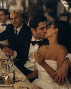 a man and woman kissing at a dinner table