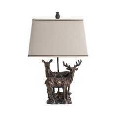 a lamp that is sitting on top of a wooden base with two deer statues underneath it