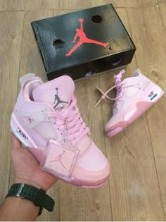 someone is holding up their pink air jordan shoes in front of a box and shoelaces