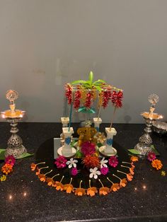 an arrangement of flowers and candles on a black countertop in front of a white wall