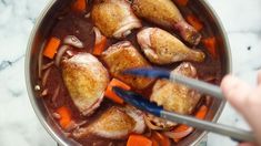 someone is stirring chicken and carrots in a pot