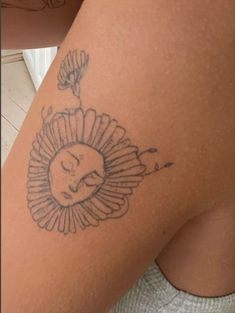 a woman's thigh with a sunflower tattoo on the side and a sleeping face