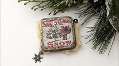 a christmas ornament hanging from the side of a tree with snow on it