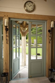 the clock is on the wall above the double doors in the entryway to the house