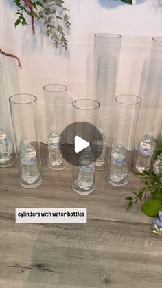 several clear vases with water bottles sitting on a table