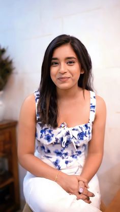 a woman sitting on top of a wooden floor next to a white wall with blue flowers