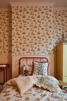 a bedroom with a teddy bear on the bed and wall papered walls behind it