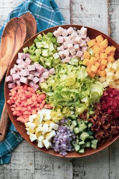 a bowl filled with chopped vegetables next to a wooden spoon on top of a table