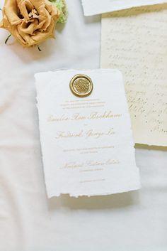 the wedding stationery is laid out on top of the bed, with an orange rose