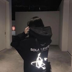 a woman in black jacket with white light up letters on it's back and the words solar system printed on her shirt