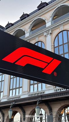 a train station sign in front of a large building with arched windows and an awning