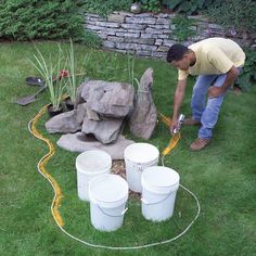 a man is working in the yard with buckets and water hose on the grass