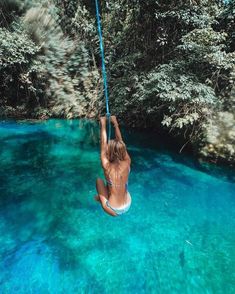 a woman hanging from a rope in the water