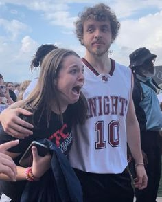 a man and woman standing next to each other in front of a group of people