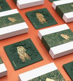 green and white cards with gold foil on them sitting on an orange tablecloth covered surface