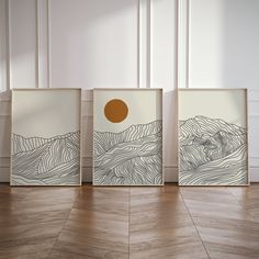 three framed art pieces on the floor in an empty room