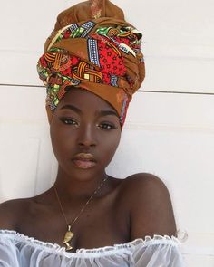 a woman wearing a turban in front of a white wall