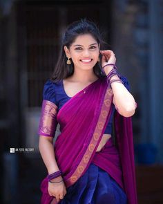 a woman wearing a purple sari and smiling at the camera with her hand on her shoulder