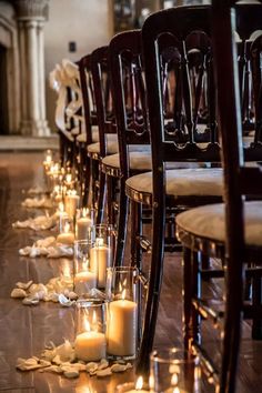 rows of chairs lined up with candles on the floor and petals scattered all around them