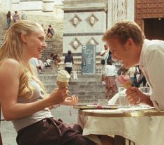 a man and woman sitting at a table eating ice cream