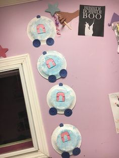 paper plates are arranged in the shape of houses on a pink wall next to a mirror