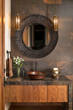 a bathroom vanity with a round mirror above it and a wooden bowl on the counter