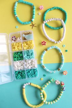 several bracelets and beads are arranged on a blue and yellow table with plastic containers