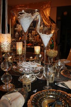 a table topped with lots of glasses filled with liquid next to candles and plates covered in confetti