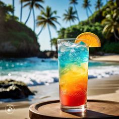 a colorful drink sitting on top of a wooden table next to the ocean and palm trees