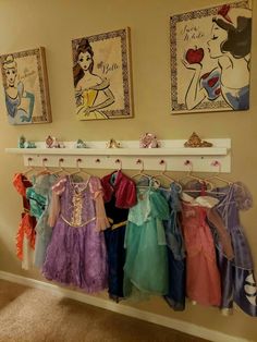 there are many princess dresses hanging on the clothes rack in this room with pictures above them