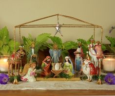 a nativity scene with figurines and candles in front of them on a table