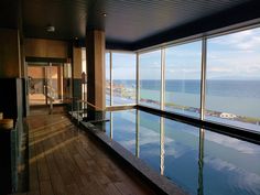 an indoor swimming pool with large windows overlooking the ocean