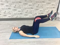 a woman is doing an exercise on a blue mat in front of a brick wall