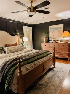 a bed room with a neatly made bed and a ceiling fan in it's corner