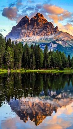 a mountain is reflected in the still water of a lake with pine trees on both sides