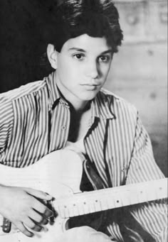 an old photo of a young man holding a guitar