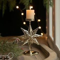 a candle holder with a star on it sitting next to a window sill filled with christmas decorations