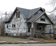 an old run down house sitting on the side of a road