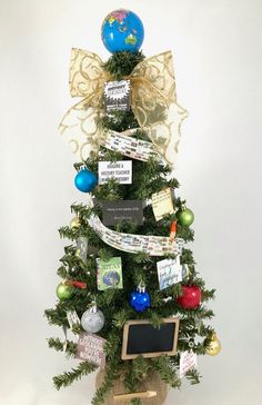 a small christmas tree with ornaments and tags on it's top, in front of a white background