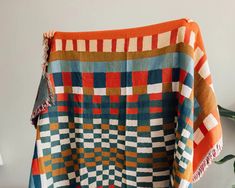 an orange and blue blanket sitting on top of a wooden table next to a potted plant