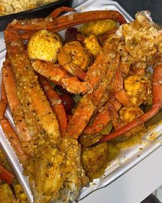 crab legs and other seafood are on display in plastic trays, along with rice