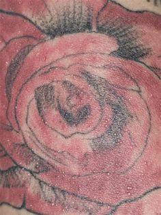 a rose tattoo on the back of a woman's shoulder