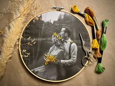 a couple is kissing in front of some flowers and scissors on a table with yarn