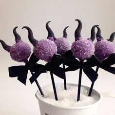 purple cake pops decorated with black horns and bowknots in a glass vase